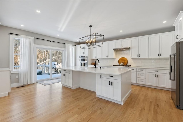 kitchen featuring pendant lighting, white cabinetry, an island with sink, and appliances with stainless steel finishes