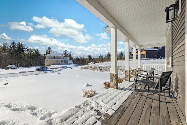 snow covered deck featuring a porch