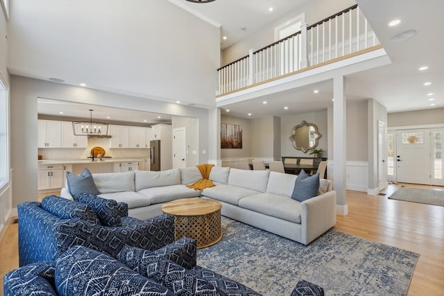 living room featuring an inviting chandelier, a high ceiling, and light wood-type flooring