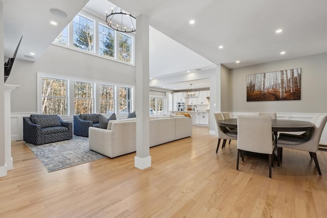 living room featuring a high ceiling, a notable chandelier, and light hardwood / wood-style floors