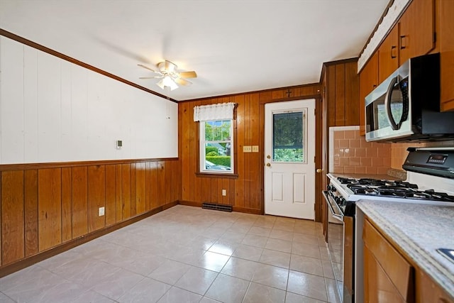 209 Sharp St, Dartmouth, MA 02747 - kitchen with stainless steel appliances, wooden walls, ornamental molding, brown cabinets, and a ceiling fan