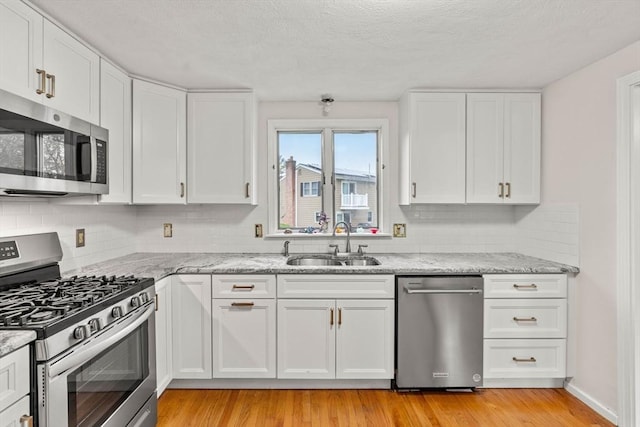 11 Douglas Ave, Burlington, MA 01803 - kitchen with appliances with stainless steel finishes, a sink, decorative backsplash, white cabinetry, and a textured ceiling