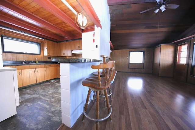 kitchen featuring beamed ceiling, hanging light fixtures, wood ceiling, a breakfast bar area, and dark hardwood / wood-style flooring