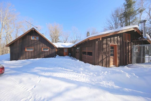 snow covered rear of property with a garage