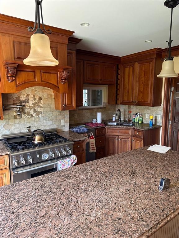 464 Canton St, Stoughton, MA 02072 - kitchen featuring backsplash, gas range, dark stone countertops, brown cabinets, and a sink