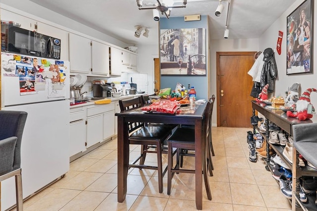 kitchen featuring rail lighting, white cabinets, light tile patterned floors, and white refrigerator