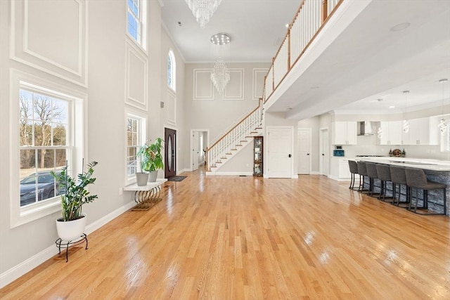 interior space featuring a notable chandelier, a towering ceiling, a healthy amount of sunlight, and light wood-type flooring