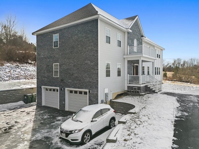 view of snowy exterior featuring a garage and a balcony