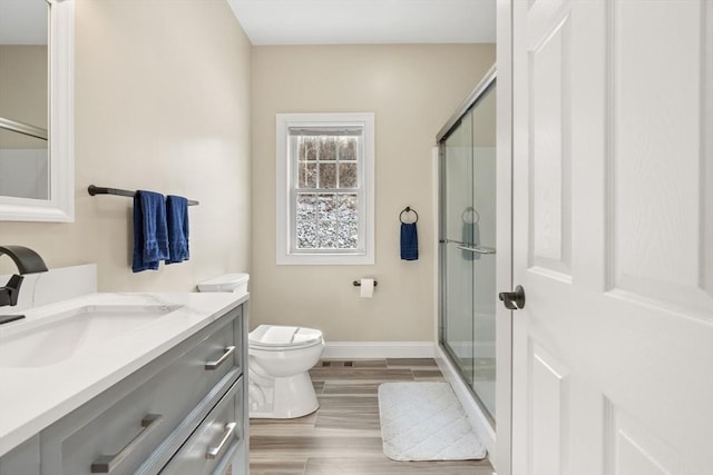 bathroom featuring vanity, toilet, hardwood / wood-style floors, and a shower with shower door