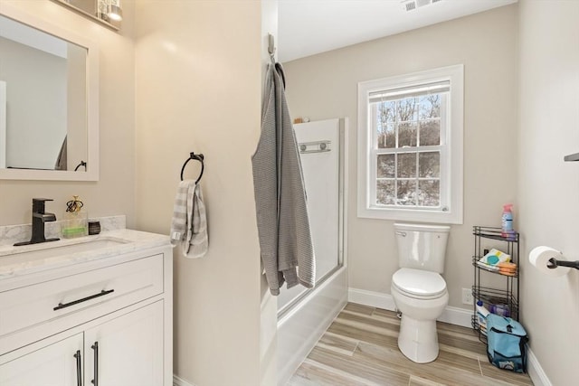 full bathroom featuring vanity, hardwood / wood-style flooring, toilet, and combined bath / shower with glass door