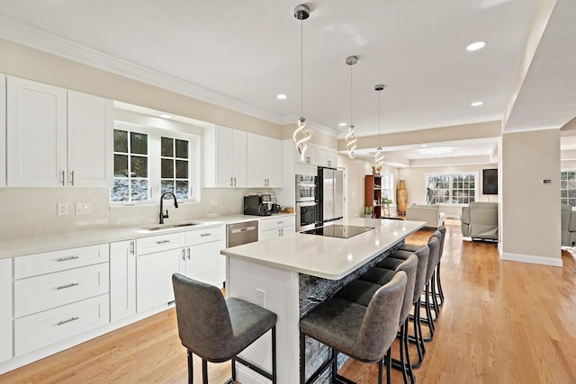 kitchen with sink, white cabinetry, decorative light fixtures, a center island, and stainless steel appliances