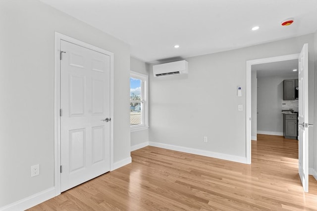 empty room featuring light hardwood / wood-style floors and an AC wall unit