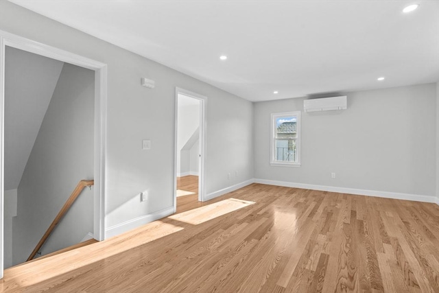 empty room featuring an AC wall unit and light hardwood / wood-style flooring