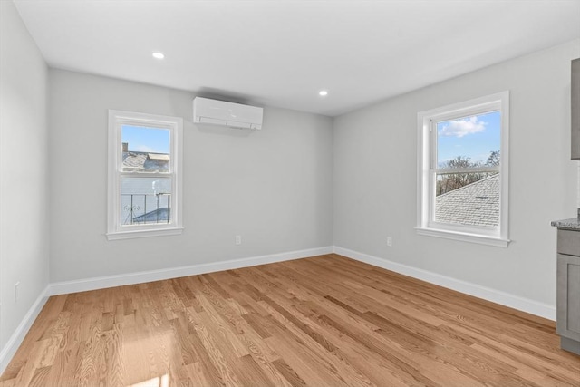 spare room featuring light hardwood / wood-style flooring and an AC wall unit