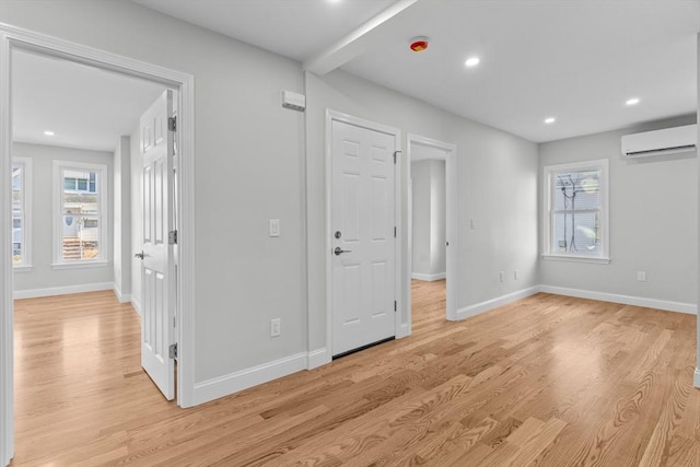 interior space featuring light hardwood / wood-style flooring, multiple windows, and a wall unit AC