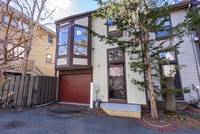 view of front of house with aphalt driveway, fence, and a garage