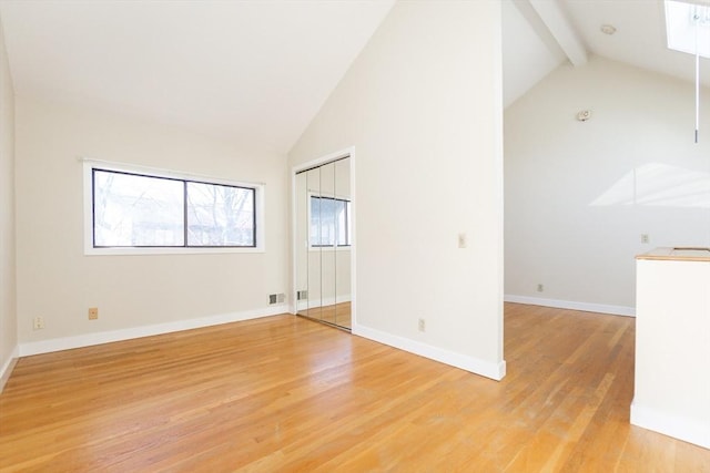 spare room with beamed ceiling, visible vents, high vaulted ceiling, light wood-style floors, and baseboards