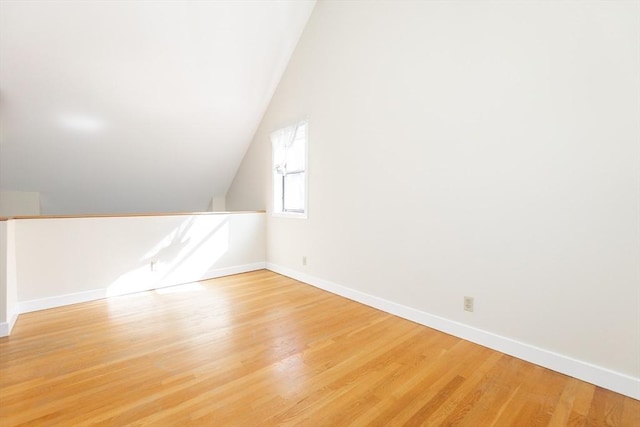 bonus room featuring baseboards, light wood-style floors, and vaulted ceiling