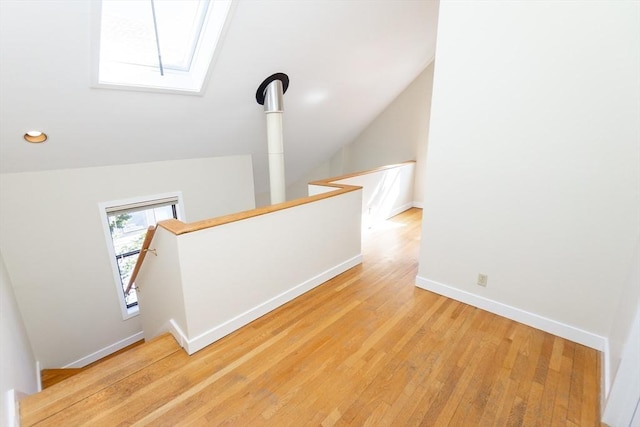 stairs featuring vaulted ceiling with skylight, recessed lighting, wood finished floors, and baseboards