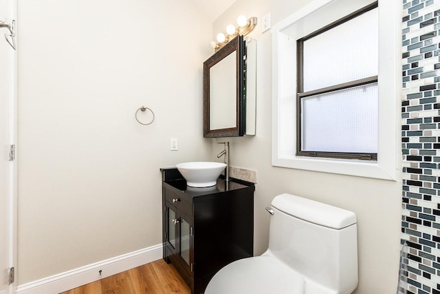 bathroom with vanity, toilet, wood finished floors, and baseboards