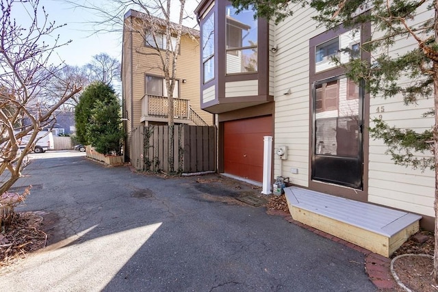 property entrance with aphalt driveway and a garage