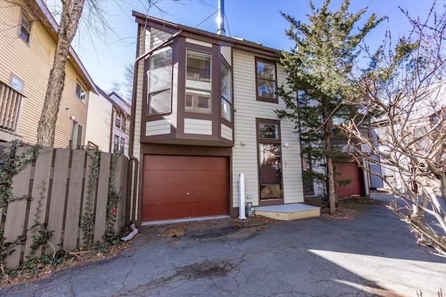 multi unit property featuring aphalt driveway, an attached garage, and fence