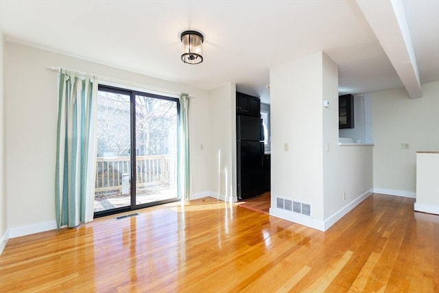 unfurnished room featuring light wood-type flooring, visible vents, and baseboards