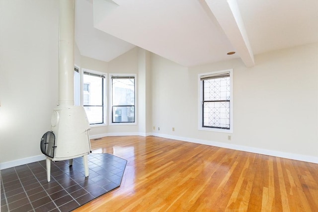 spare room featuring lofted ceiling with beams, baseboards, and wood finished floors