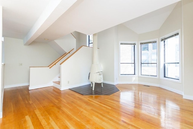 unfurnished living room featuring stairway, wood finished floors, baseboards, visible vents, and vaulted ceiling