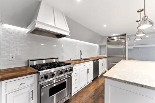 56 Cart Path Rd, Weston, MA 02493 - kitchen with high quality appliances, tasteful backsplash, premium range hood, butcher block counters, and white cabinetry