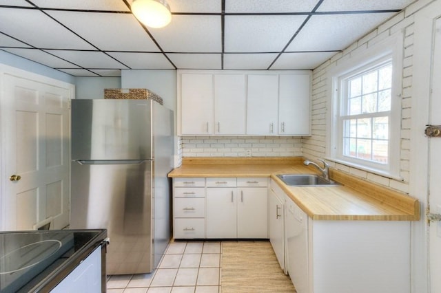 kitchen with white cabinetry, stainless steel fridge, sink, and a drop ceiling