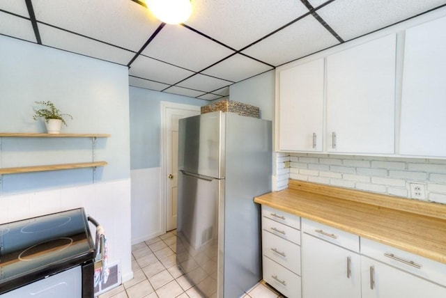 kitchen with stainless steel refrigerator, white cabinetry, light tile patterned floors, a drop ceiling, and electric stove