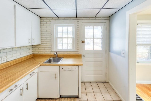 kitchen with sink, light tile patterned floors, a paneled ceiling, white cabinetry, and white dishwasher