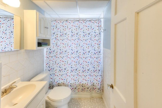 full bathroom with vanity, tile walls, shower / tub combo with curtain, and toilet