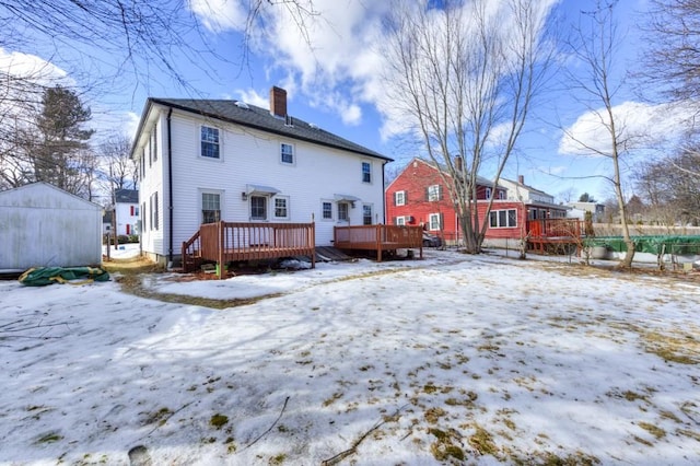 snow covered rear of property with a deck