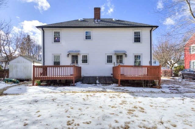 snow covered rear of property with a deck