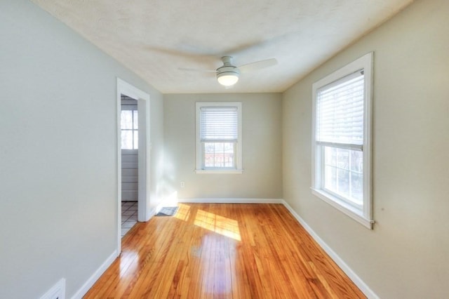 spare room with ceiling fan, plenty of natural light, and light wood-type flooring