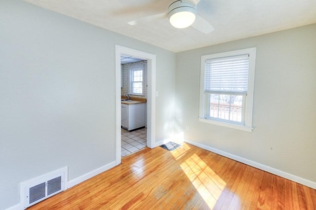 unfurnished room with sink, light hardwood / wood-style floors, and ceiling fan