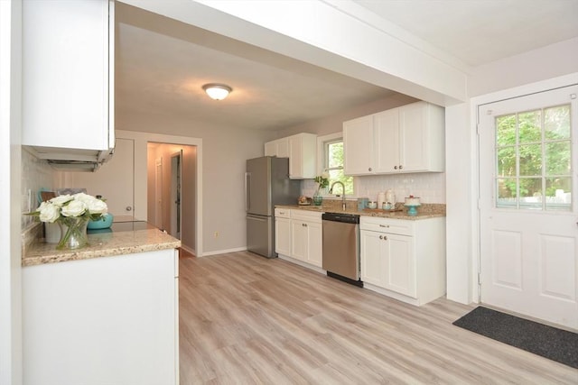 16 W St, Natick, MA 01760 - kitchen featuring stainless steel appliances, white cabinets, light wood-style flooring, and backsplash