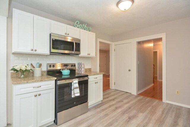 16 W St, Natick, MA 01760 - kitchen with stainless steel appliances, light wood-style flooring, white cabinetry, backsplash, and baseboards
