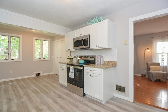 16 W St, Natick, MA 01760 - kitchen with appliances with stainless steel finishes, light wood finished floors, backsplash, light stone counters, and white cabinets