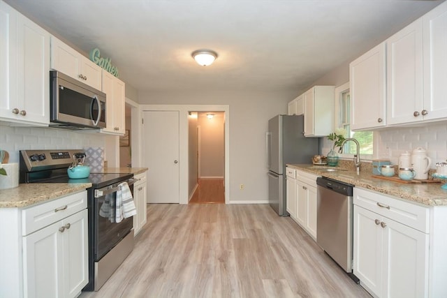 16 W St, Natick, MA 01760 - kitchen with stainless steel appliances, a sink, decorative backsplash, white cabinetry, and light wood-style floors
