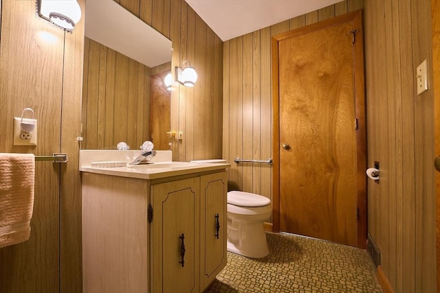 bathroom with vanity, tile patterned floors, toilet, and wood walls