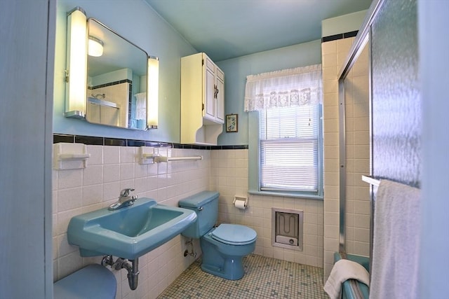 bathroom featuring toilet, tile patterned flooring, and tile walls