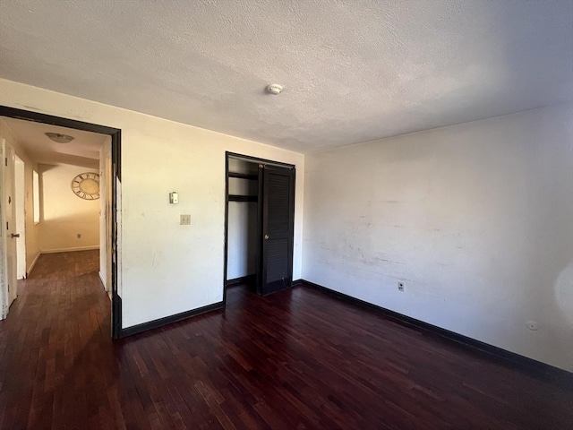 unfurnished bedroom with a textured ceiling, a closet, baseboards, and dark wood-type flooring