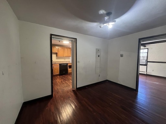 unfurnished room with dark wood-type flooring, a ceiling fan, and baseboards