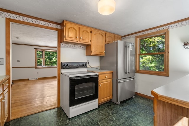 kitchen featuring white electric range oven, dark wood-type flooring, stainless steel refrigerator, and a healthy amount of sunlight