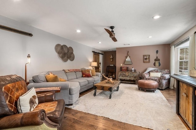 living room with ceiling fan, a barn door, hardwood / wood-style flooring, and recessed lighting