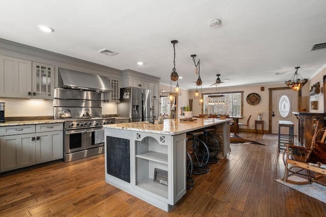 kitchen featuring visible vents, wall chimney exhaust hood, stainless steel appliances, gray cabinetry, and open shelves