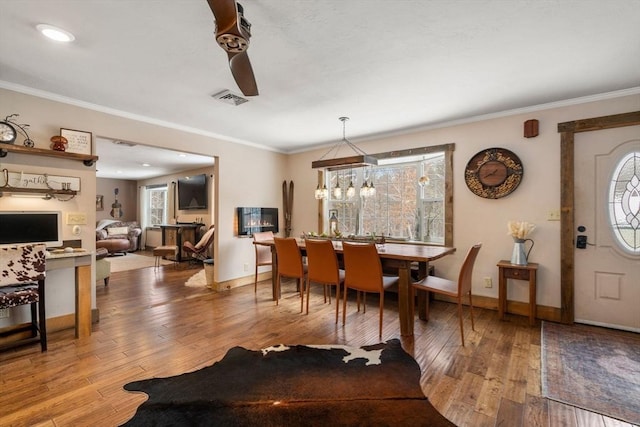 dining room with baseboards, hardwood / wood-style floors, visible vents, and crown molding